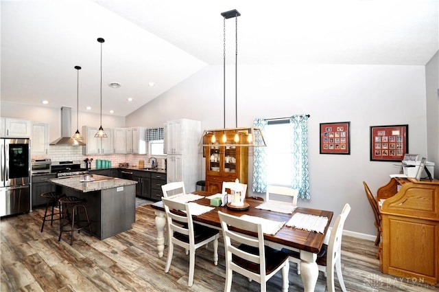 dining space featuring sink, hardwood / wood-style flooring, and high vaulted ceiling