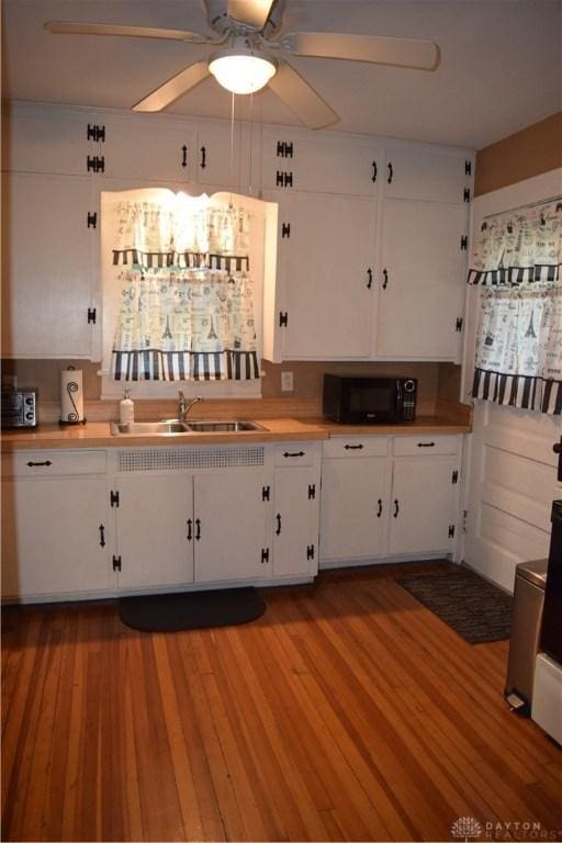 kitchen with white cabinets, black microwave, a ceiling fan, and a sink
