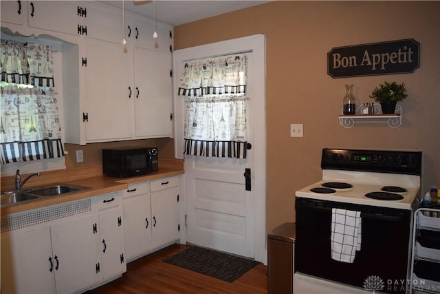 kitchen with white cabinets, a sink, range with electric cooktop, black microwave, and light countertops