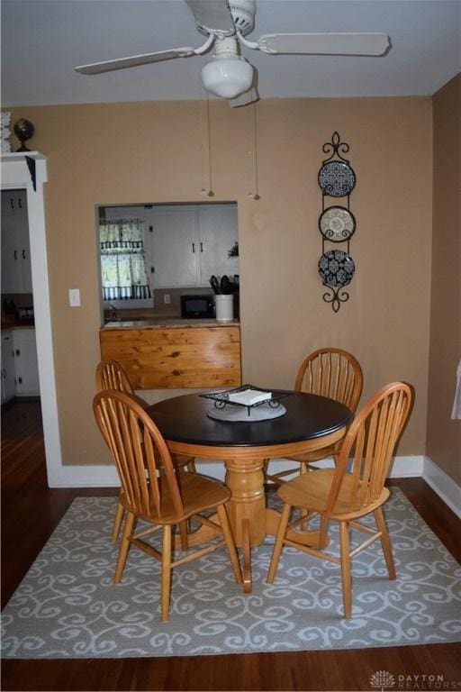 dining area with ceiling fan and dark hardwood / wood-style floors