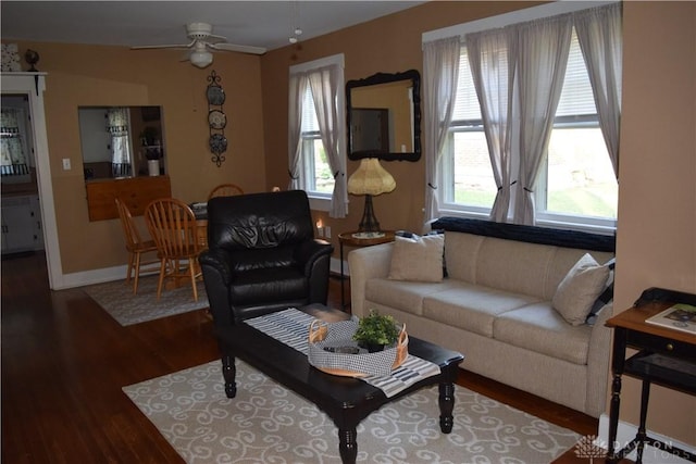 living area featuring baseboards, a ceiling fan, and wood finished floors