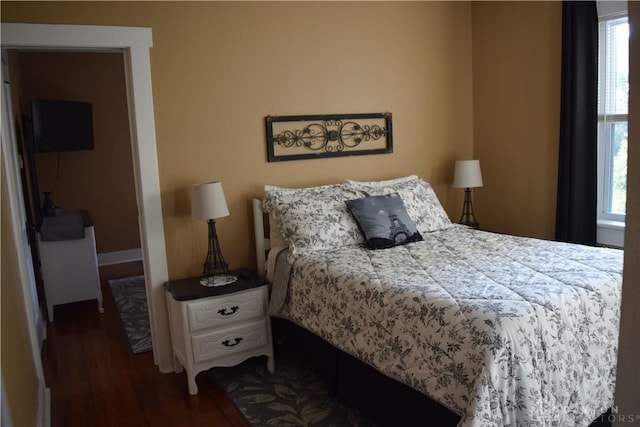 bedroom with dark hardwood / wood-style floors and multiple windows