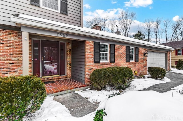 snow covered property entrance with a garage