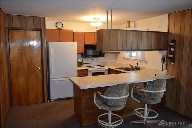 kitchen featuring sink, white appliances, a breakfast bar, decorative light fixtures, and kitchen peninsula