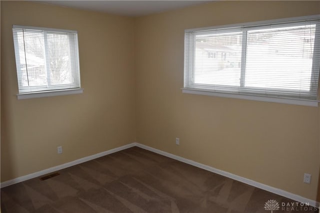 unfurnished room with dark colored carpet