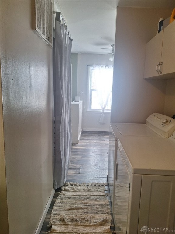 clothes washing area featuring hardwood / wood-style flooring, ceiling fan, separate washer and dryer, and cabinets