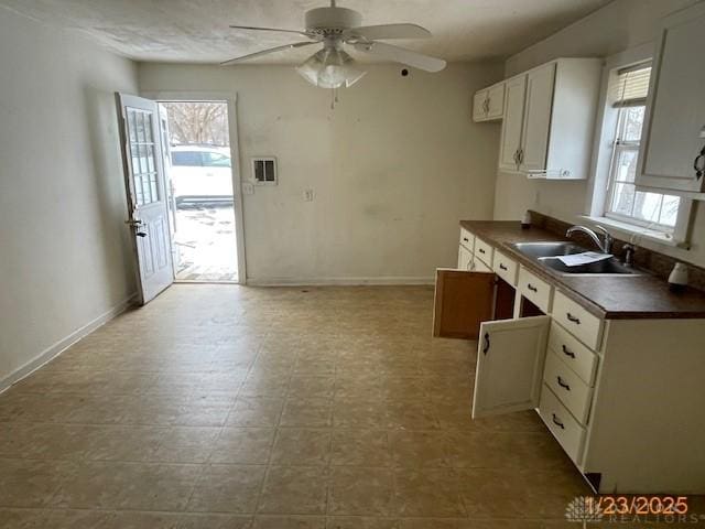 kitchen featuring ceiling fan, sink, and white cabinets