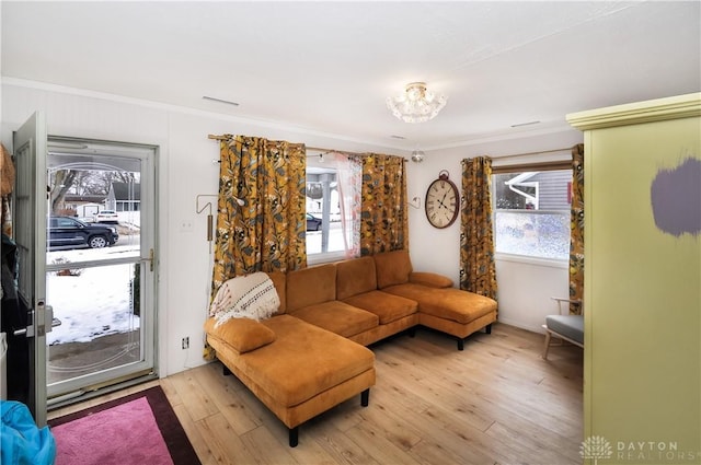 living room featuring crown molding, a healthy amount of sunlight, and light hardwood / wood-style floors