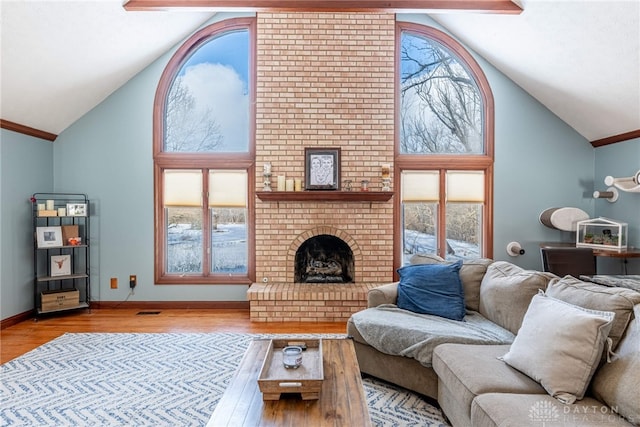 living room featuring a healthy amount of sunlight, a fireplace, high vaulted ceiling, and light wood-type flooring