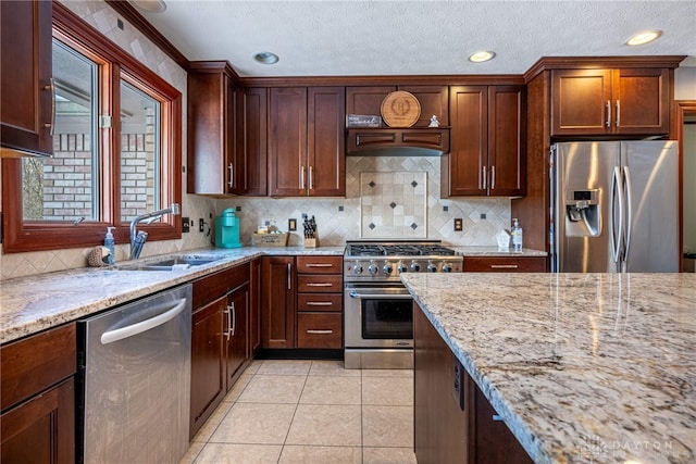 kitchen with sink, light stone counters, light tile patterned floors, stainless steel appliances, and backsplash