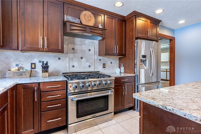 kitchen with backsplash, light tile patterned floors, stainless steel appliances, and light stone countertops