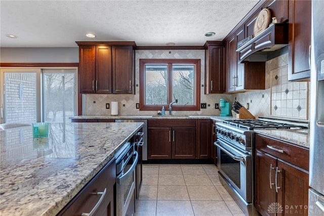 kitchen featuring light stone countertops, sink, stainless steel range, and backsplash