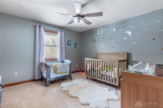 carpeted bedroom with a nursery area and ceiling fan