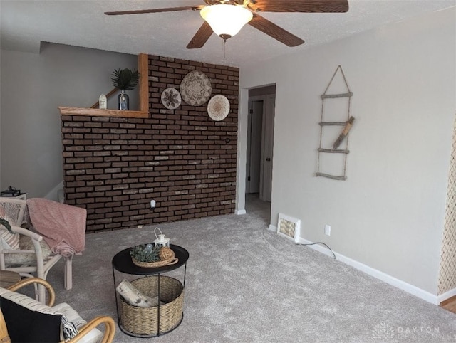 living area with ceiling fan, carpet floors, and a textured ceiling