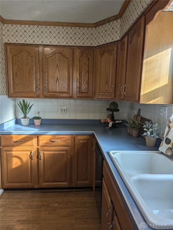 kitchen featuring sink, ornamental molding, dark hardwood / wood-style floors, dishwasher, and decorative backsplash