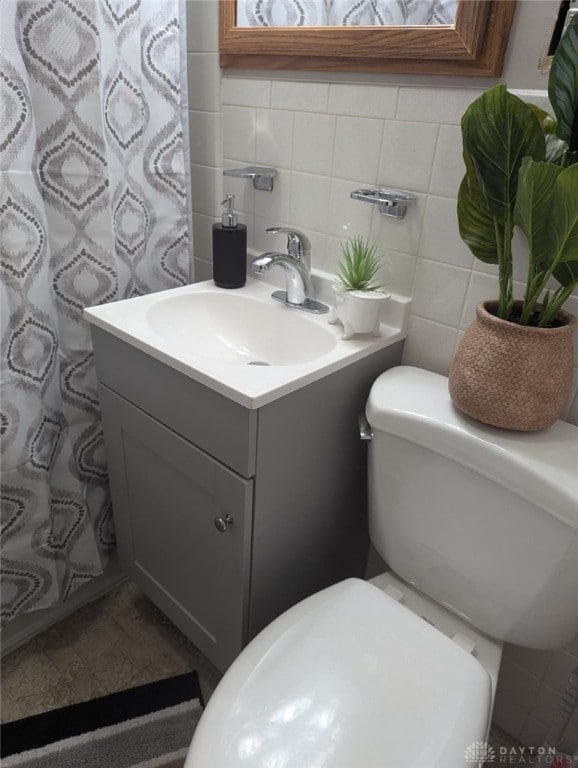 bathroom featuring vanity, toilet, and tile walls