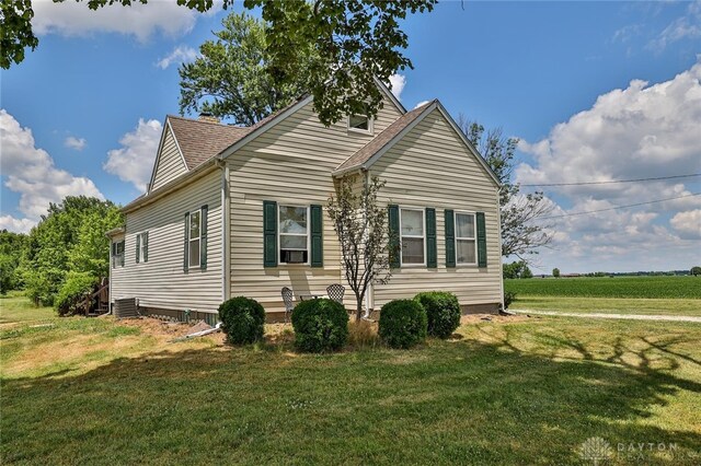 view of side of home with a shingled roof and a yard