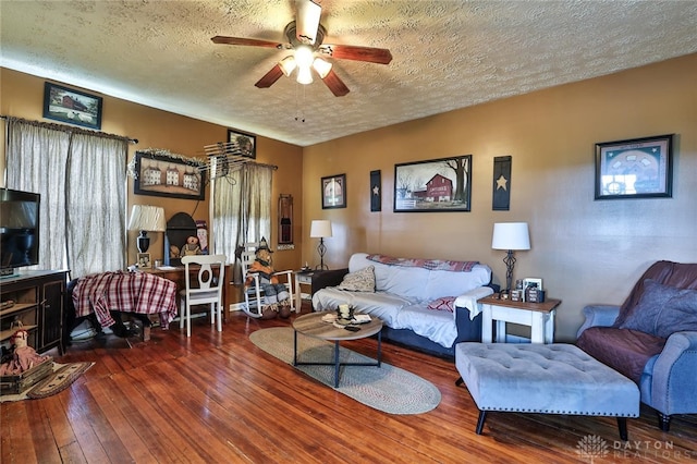 living room featuring hardwood / wood-style flooring, a ceiling fan, and a textured ceiling