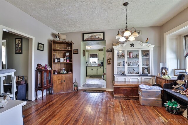 dining space featuring hardwood / wood-style flooring, a notable chandelier, and a textured ceiling