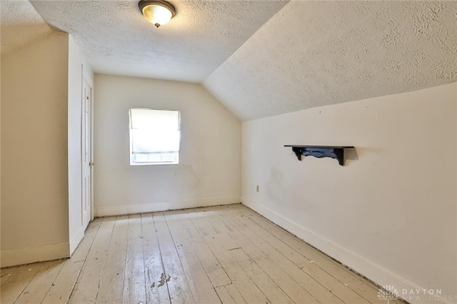 bonus room with wood-type flooring, baseboards, vaulted ceiling, and a textured ceiling