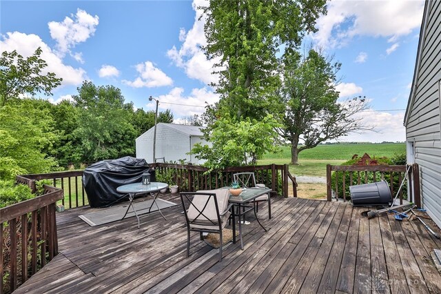 wooden terrace featuring a grill, a lawn, and outdoor dining space