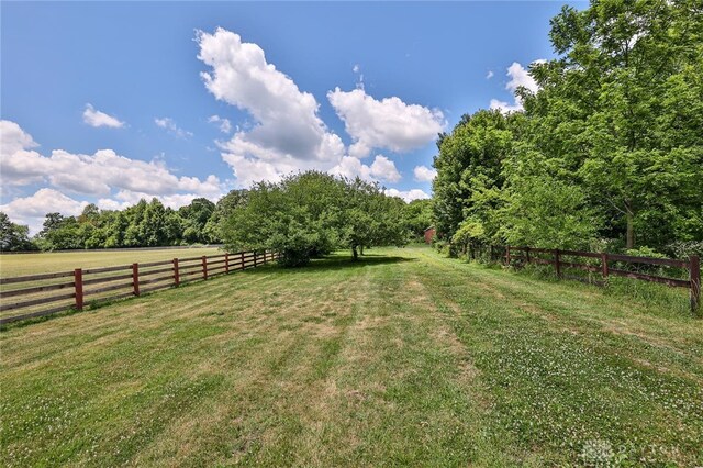 view of yard with fence and a rural view