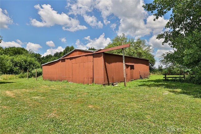 view of side of property with an outbuilding, a pole building, and a lawn