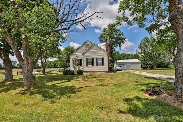 view of front of property with a front lawn, a chimney, a detached garage, and fence