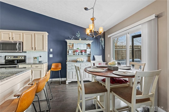 dining area with an inviting chandelier, baseboards, dark wood finished floors, and a textured ceiling