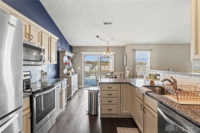 kitchen with visible vents, appliances with stainless steel finishes, dark wood-type flooring, a peninsula, and a sink