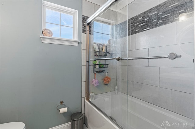 full bath featuring bath / shower combo with glass door, toilet, and baseboards