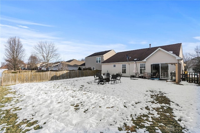 snow covered rear of property featuring an outdoor fire pit and fence