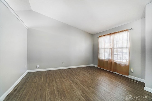 unfurnished room featuring lofted ceiling and dark hardwood / wood-style flooring