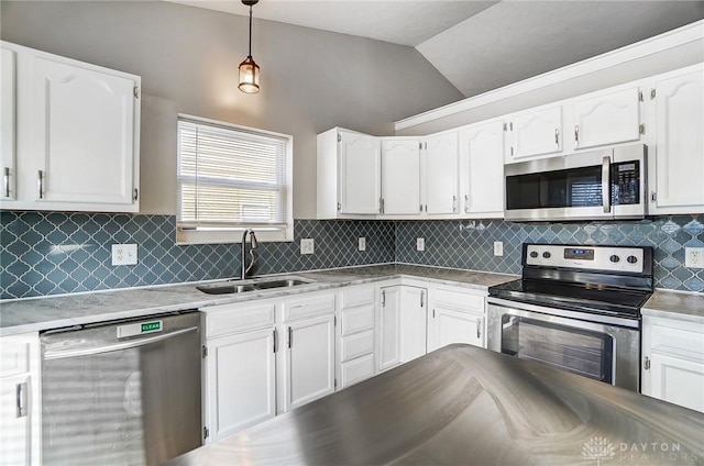 kitchen featuring vaulted ceiling, appliances with stainless steel finishes, sink, white cabinets, and hanging light fixtures