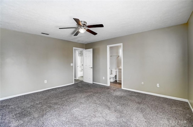 unfurnished bedroom featuring dark carpet, a textured ceiling, ceiling fan, and ensuite bath