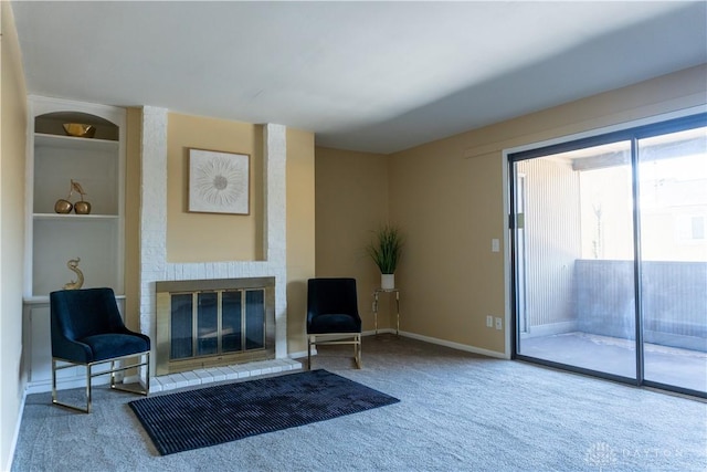 sitting room with built in shelves, carpet, and a brick fireplace