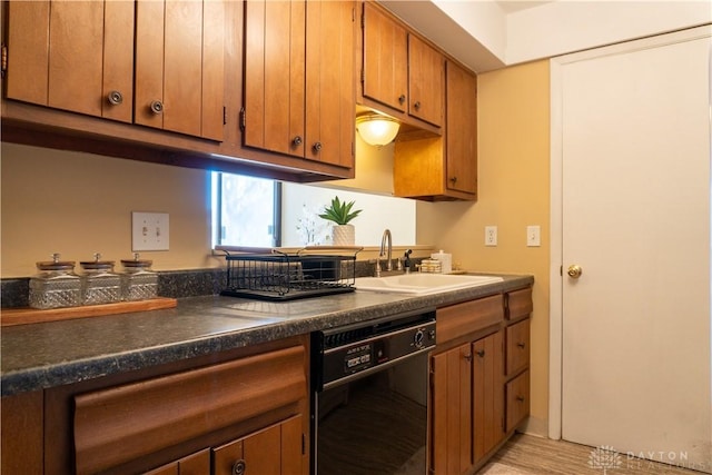 kitchen with a sink, dark countertops, brown cabinets, and dishwasher