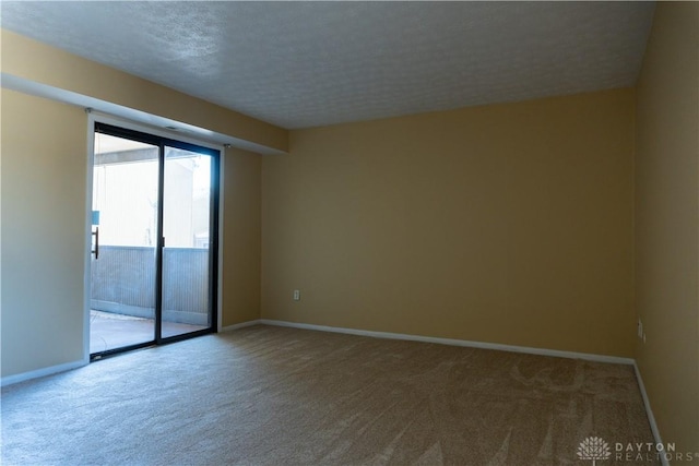 carpeted spare room featuring baseboards and a textured ceiling