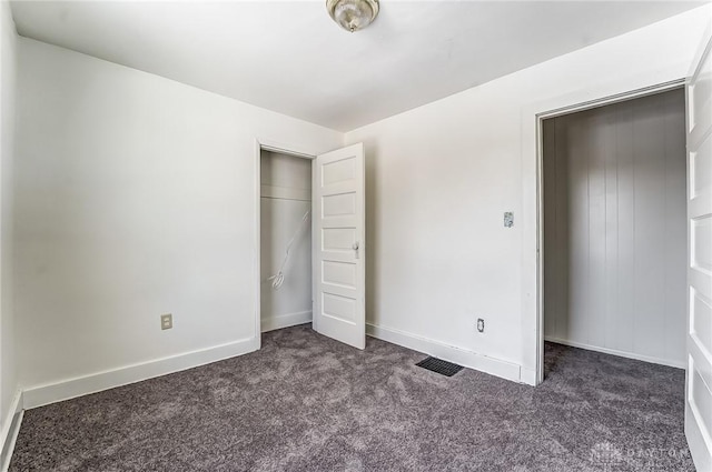 unfurnished bedroom with dark carpet and a closet