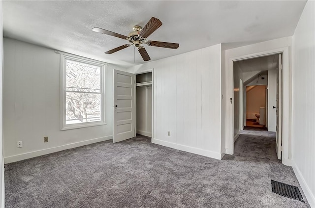 unfurnished bedroom featuring dark carpet, ceiling fan, and a closet