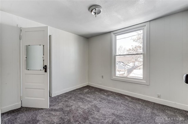 unfurnished room featuring a textured ceiling and dark colored carpet