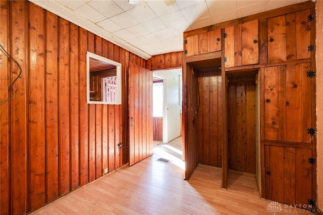 corridor featuring wooden walls and light wood-type flooring