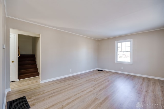 spare room featuring crown molding and light wood-type flooring