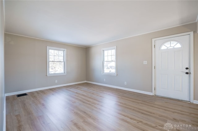 entryway with crown molding, a wealth of natural light, and light hardwood / wood-style flooring