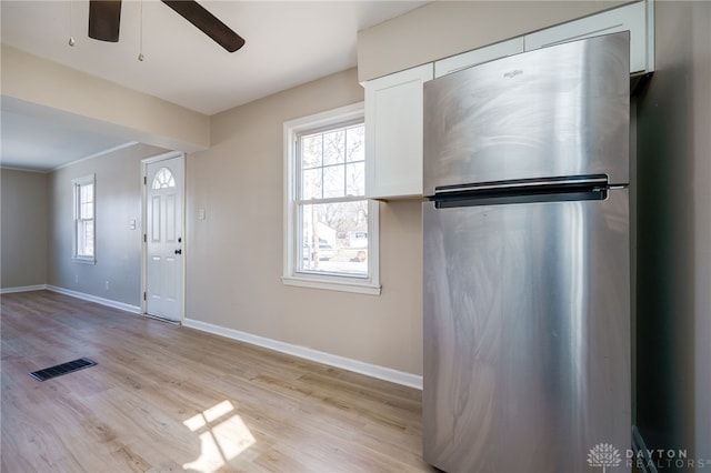 kitchen featuring plenty of natural light, stainless steel refrigerator, white cabinets, and light wood-type flooring