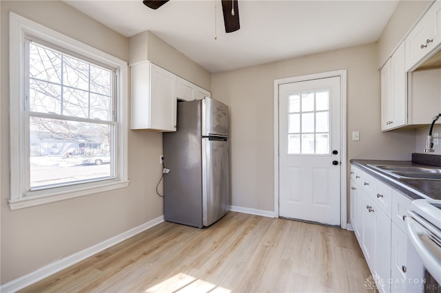 kitchen with sink, white cabinets, stainless steel refrigerator, and white stove