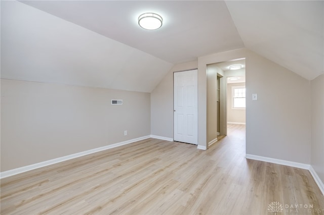 additional living space featuring vaulted ceiling and light wood-type flooring