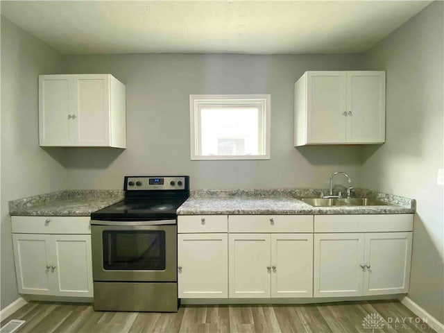 kitchen featuring light hardwood / wood-style flooring, sink, stainless steel electric range, and white cabinets