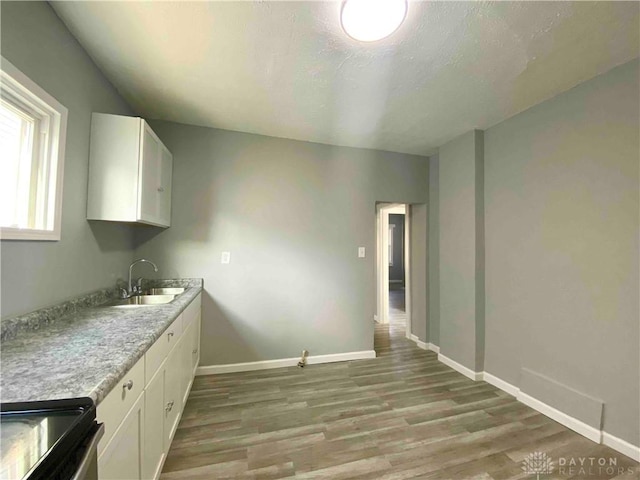 kitchen featuring electric range, light hardwood / wood-style floors, sink, and white cabinets