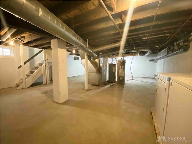 basement with washing machine and clothes dryer, water heater, heating unit, and gas water heater